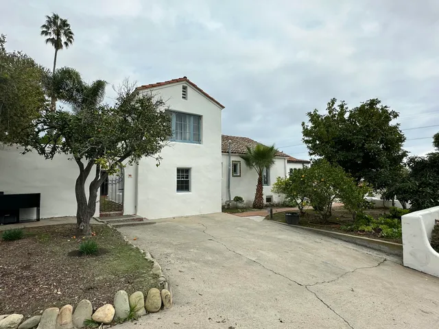 a view of a white house with a yard and large tree