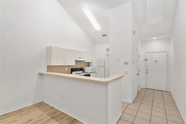 a living room with stainless steel appliances kitchen island granite countertop a refrigerator and cabinets