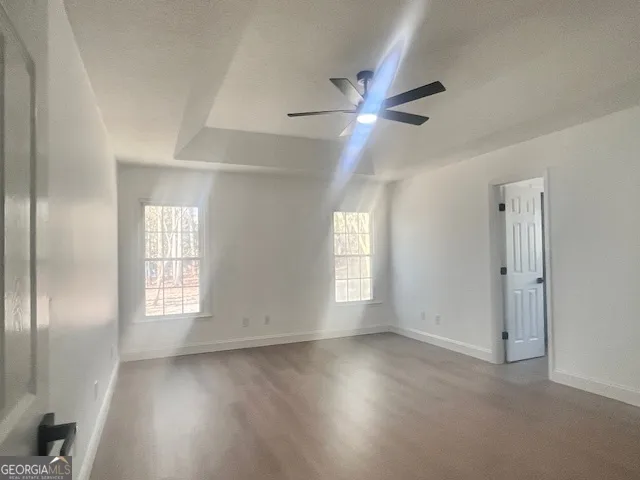 a view of empty room with wooden floor and fan
