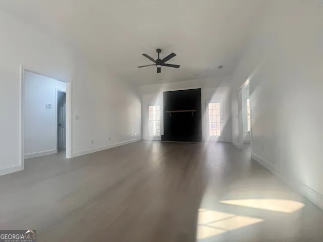 an empty room with wooden floor and ceiling fan