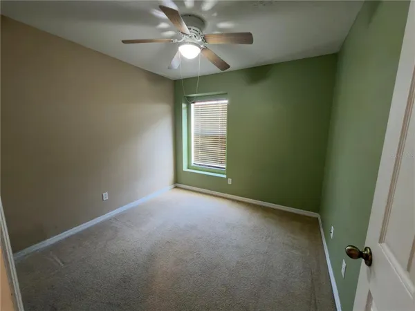 an empty room with a chandelier fan and windows