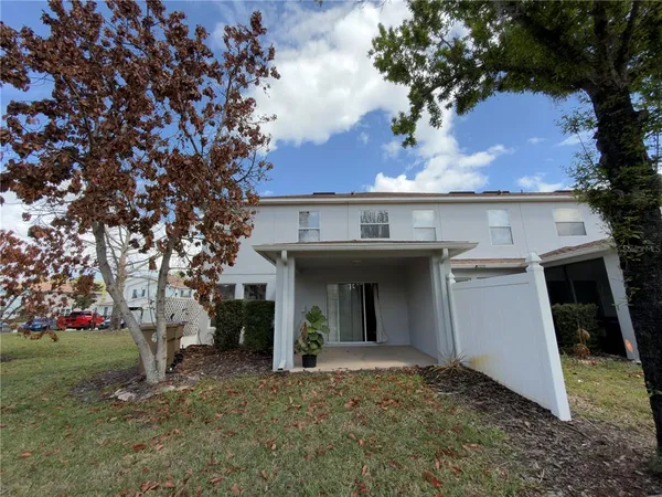 a view of a house with a yard and a large tree