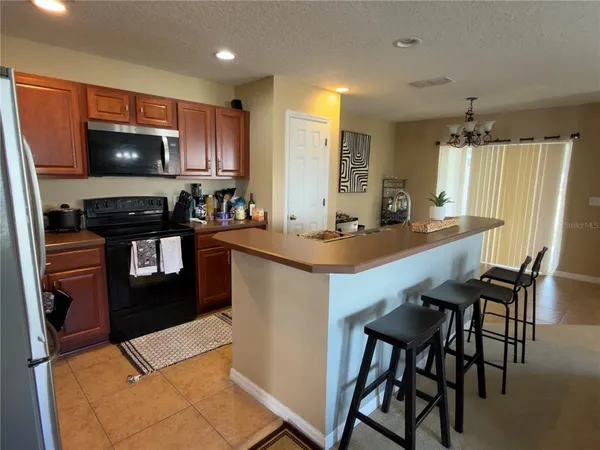 a kitchen with stainless steel appliances a stove a sink a microwave a refrigerator and chairs