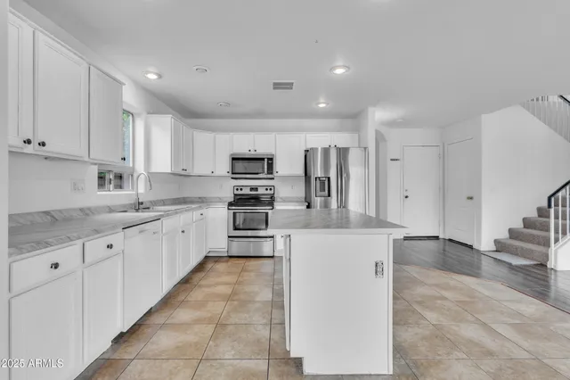 a large kitchen with stainless steel appliances cabinets a sink and a counter top space