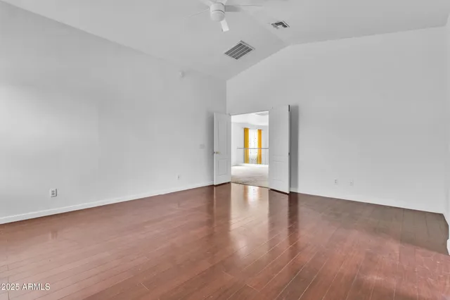 a view of an empty room with window and wooden floor