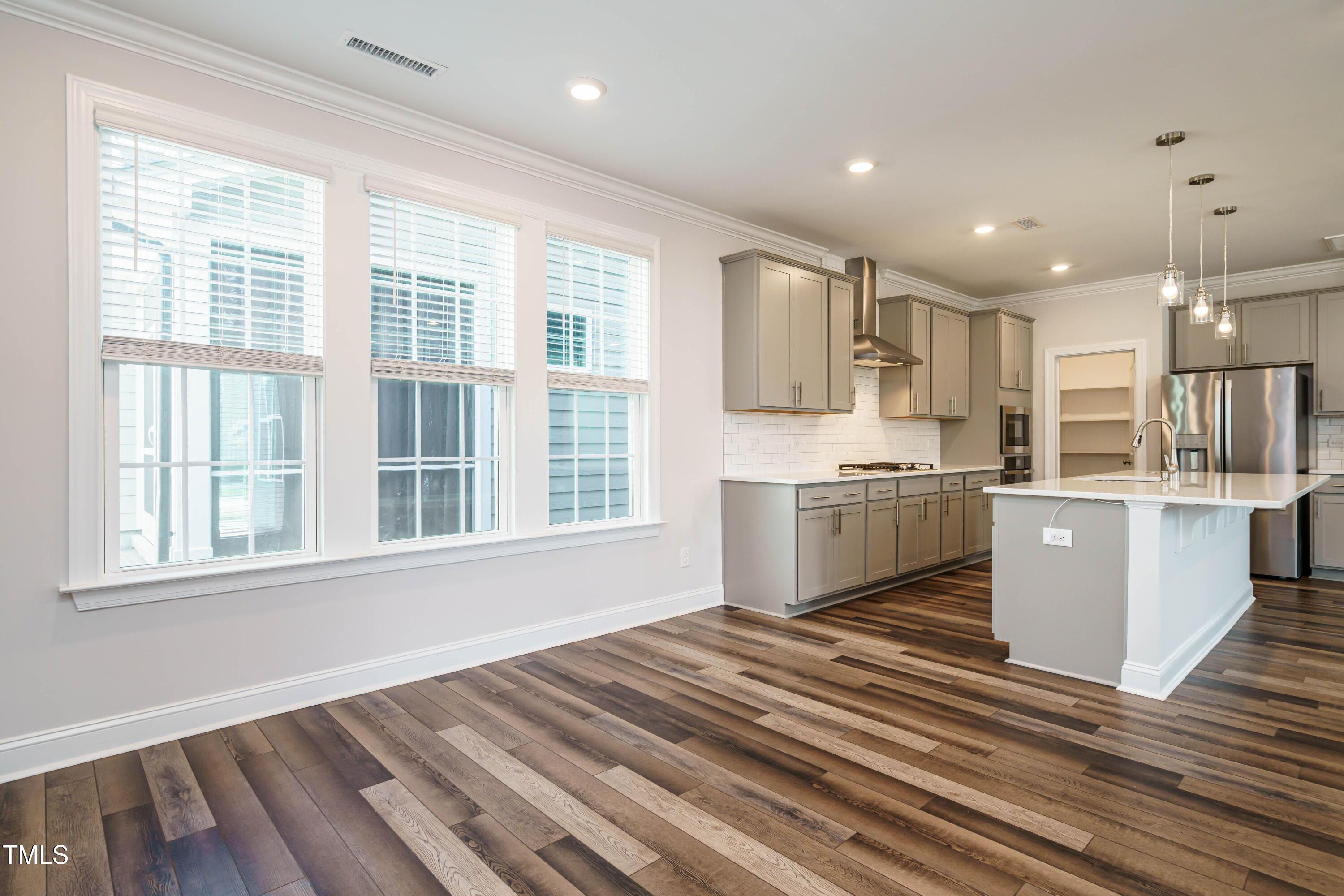 5201 Influence Way Raleigh, NC 27616 - Photo 12 of 33 a open kitchen with kitchen island a stove a sink dishwasher and white cabinets with wooden floor
