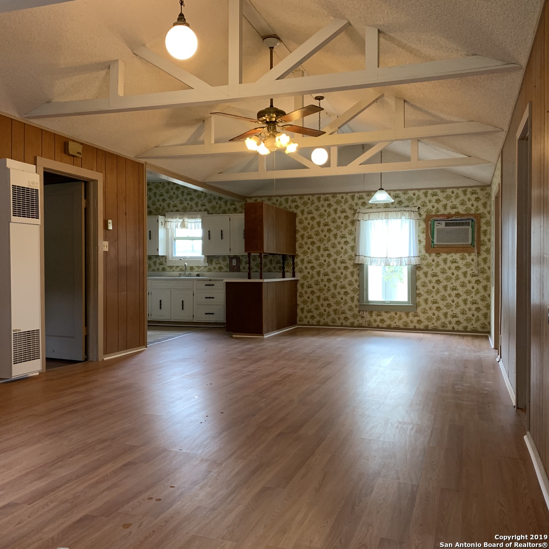an empty room with wooden floor and chandelier