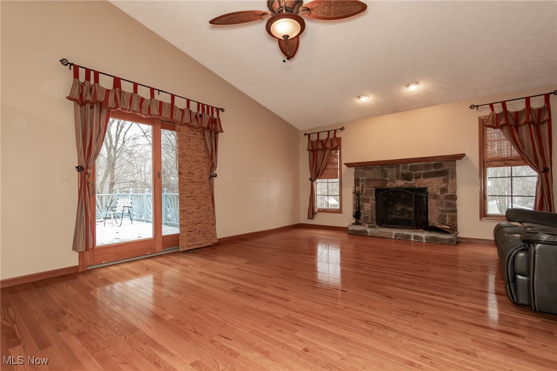 4815 South Ridge Road Perry, OH 44081 - Photo 7 of 48 Unfurnished living room featuring lofted ceiling, a stone fireplace, light wood-style flooring, and ceiling fan