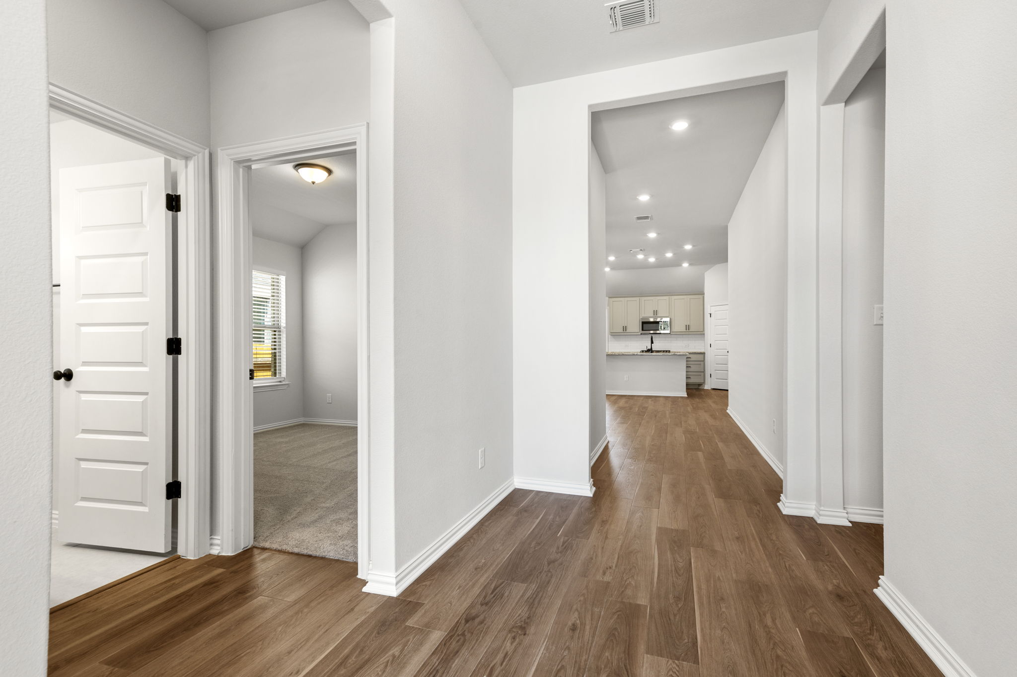 341 Fawn Riv Run Kyle, TX 78640 - Photo 3 of 29 Hall featuring baseboards, dark wood-style floors, visible vents, and recessed lighting