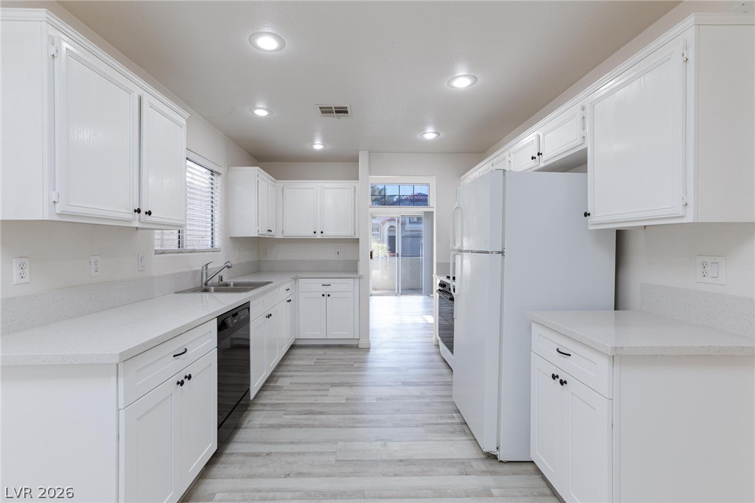 2246 Ramsgate Drive Henderson, NV 89074 - Photo 8 of 36 A well-lit kitchen with sleek white cabinetry and durable countertops, perfect for culinary endeavors.