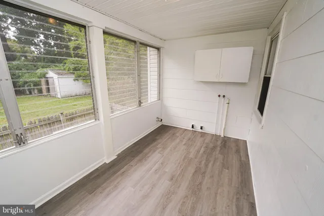 a view of an empty room with a window and hardwood floor