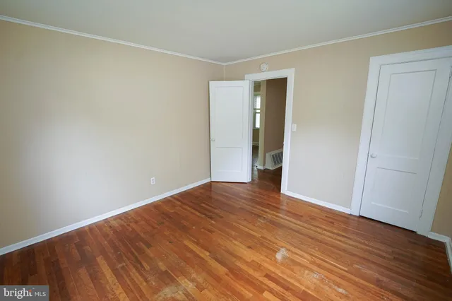 a view of an empty room with wooden floor and closet