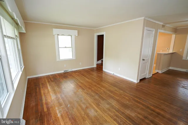 an empty room with wooden floor and windows