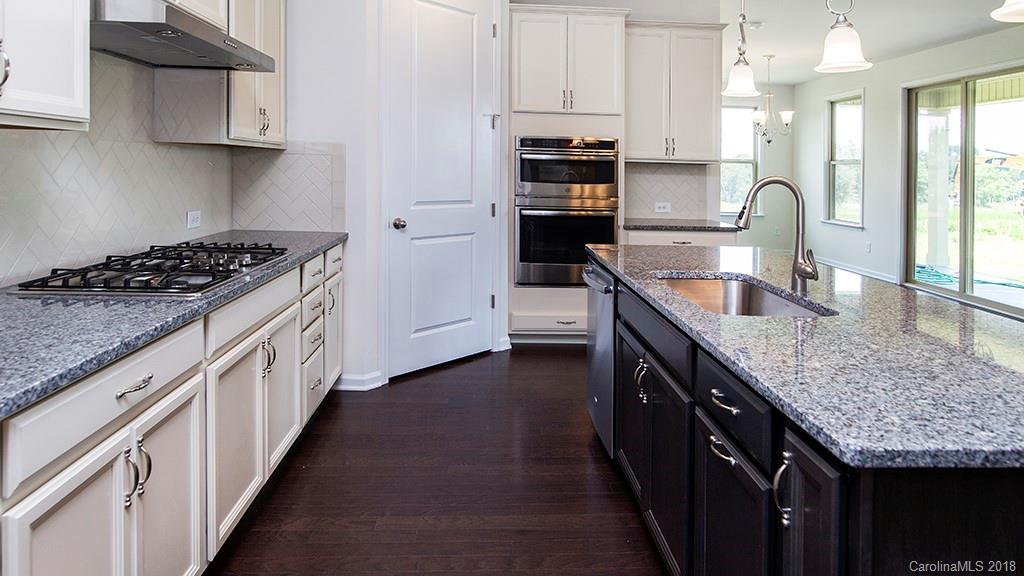 5549 Braddock Ml Way, Unit 264 Lancaster, SC 29720 - Photo 19 of 23 a kitchen with granite countertop kitchen island wooden cabinets and stainless steel appliances