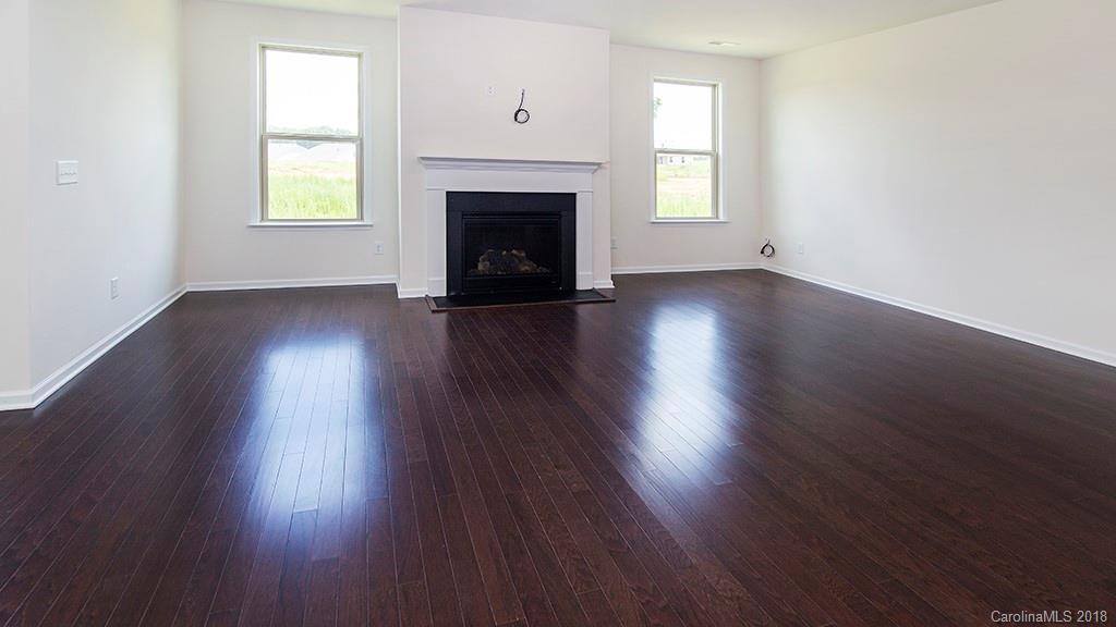 5549 Braddock Ml Way, Unit 264 Lancaster, SC 29720 - Photo 10 of 23 an empty room with wooden floor fireplace and windows
