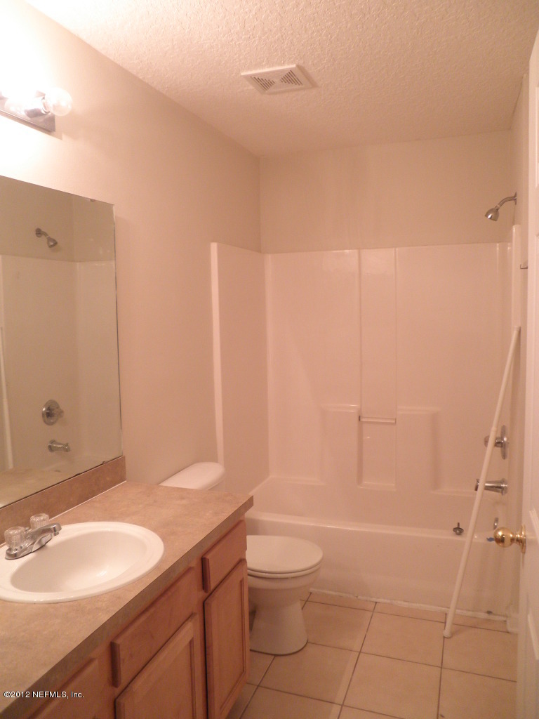 7920 Merrill Road, Unit 912 Jacksonville, FL 32277 - Photo 10 of 14 a bathroom with a granite countertop sink toilet a mirror and shower