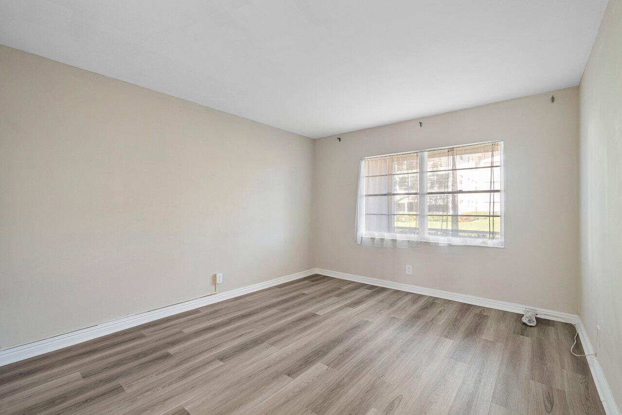 517 Fanshaw M Boca Raton, FL 33434 - Photo 20 of 28 an empty room with wooden floor and windows