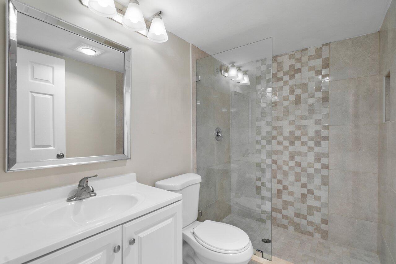517 Fanshaw M Boca Raton, FL 33434 - Photo 23 of 28 a bathroom with a sink a toilet a mirror and shower