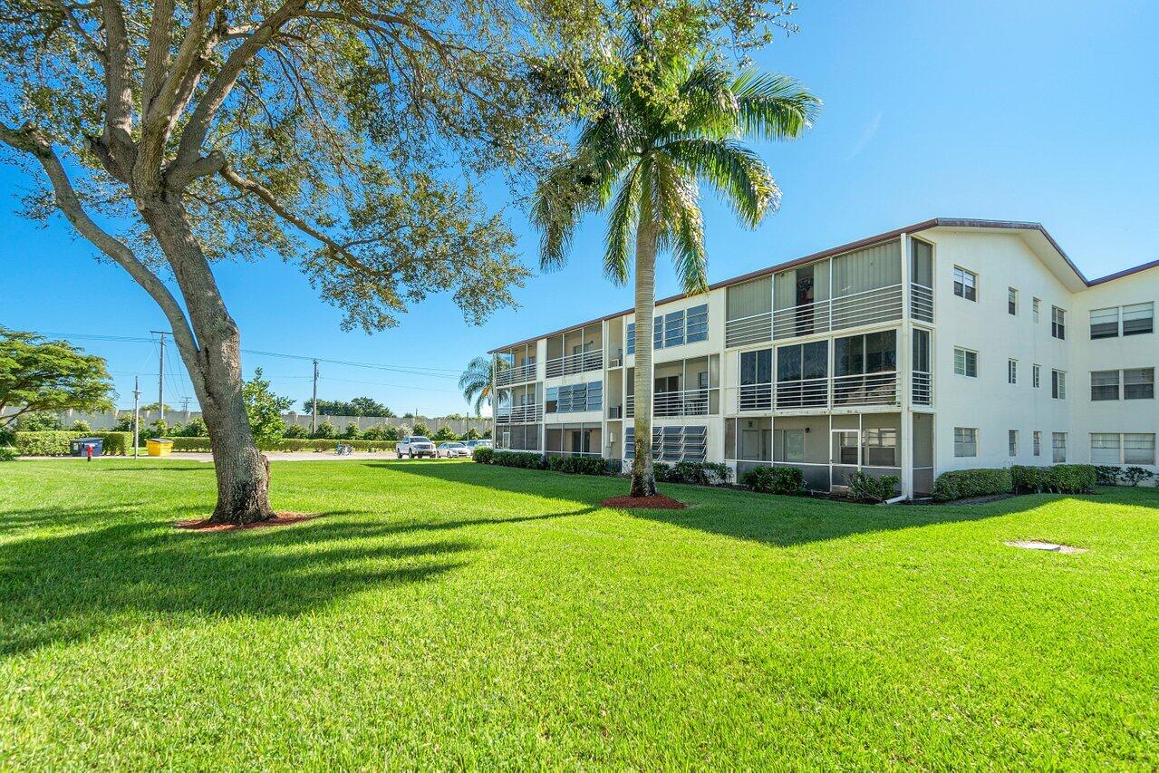 517 Fanshaw M Boca Raton, FL 33434 - Photo 27 of 28 a view of a house with a big yard and palm trees