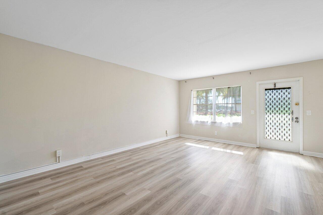 517 Fanshaw M Boca Raton, FL 33434 - Photo 7 of 28 a view of an empty room with wooden floor and a window