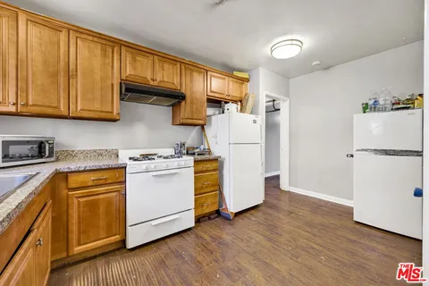 a kitchen with a refrigerator a stove cabinets wooden floor and a window