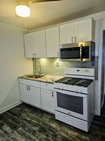 a kitchen with granite countertop a stove sink and microwave
