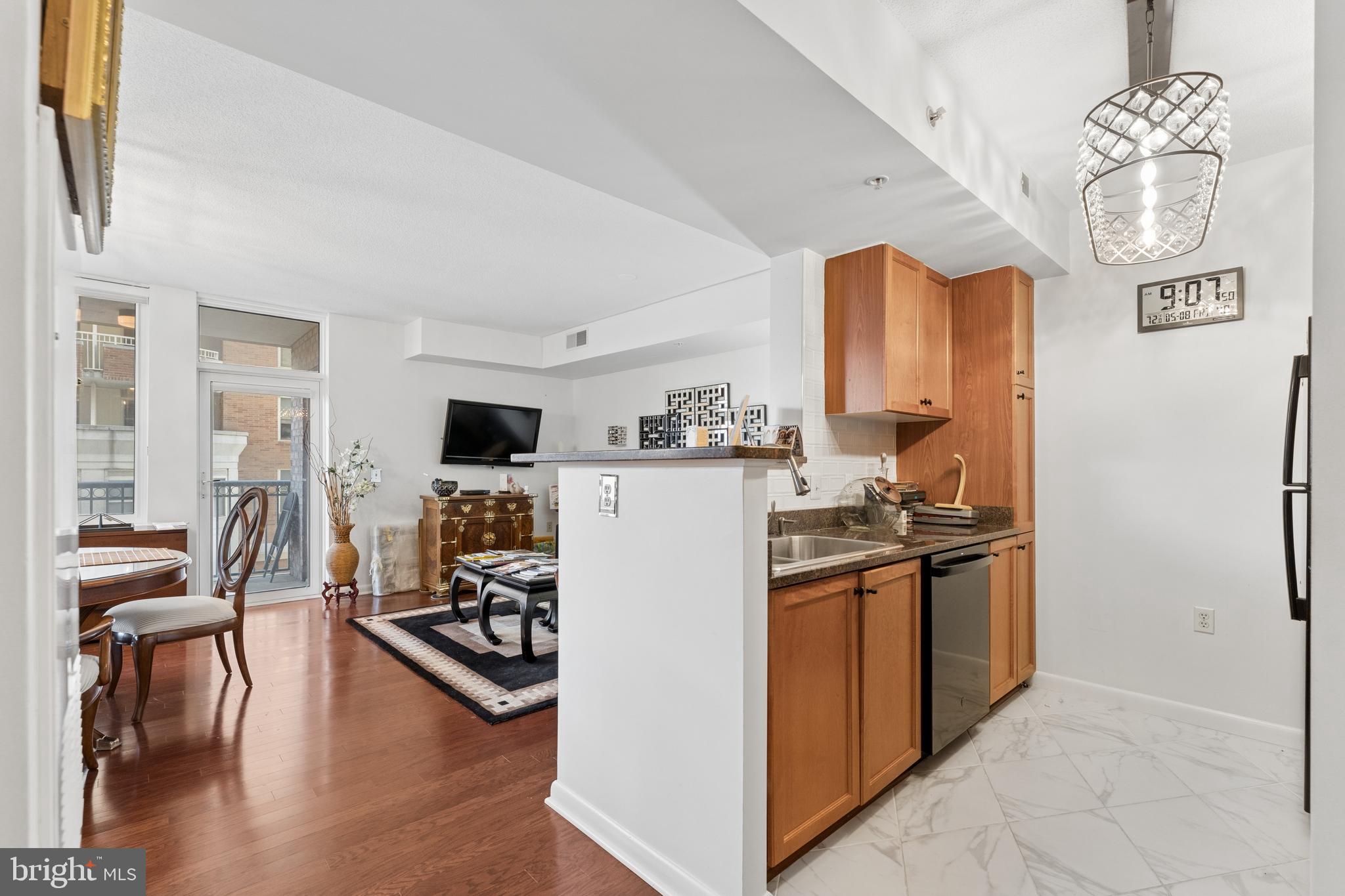 851 North Glebe Road, Unit 706 Arlington, VA 22203 - Photo 12 of 34 a kitchen with stainless steel appliances granite countertop a stove top oven a refrigerator a dining table and chairs with wooden floor