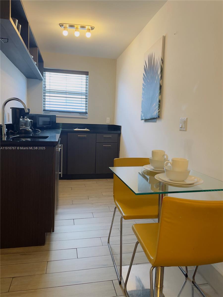 7500 Collins Avenue, Unit 112 Miami Beach, FL 33141 - Photo 2 of 10 a kitchen with a table chairs and a sink