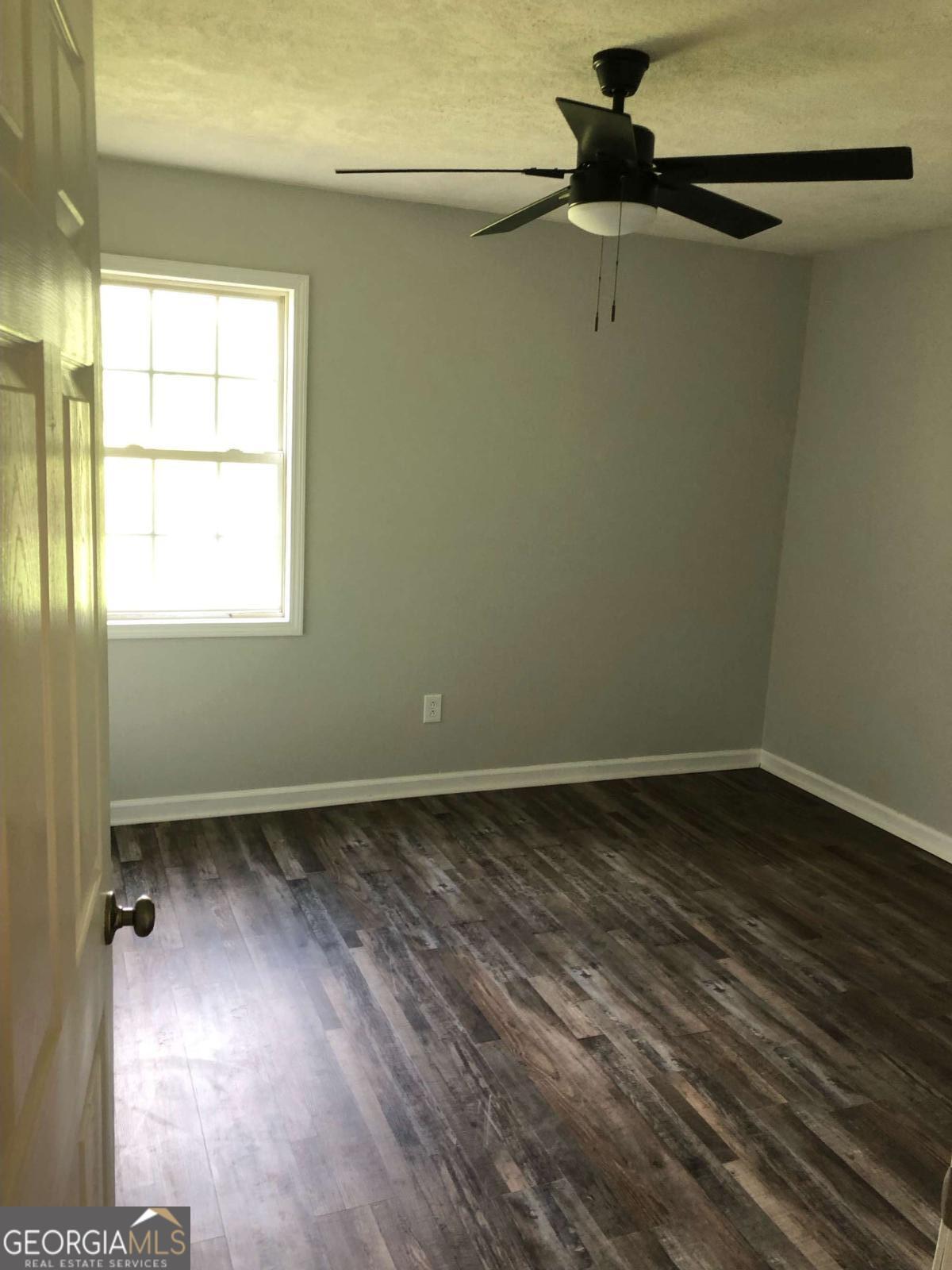 153 A Cox Road Gordon, GA 31031 - Photo 12 of 16 a view of an empty room with a window and wooden floor