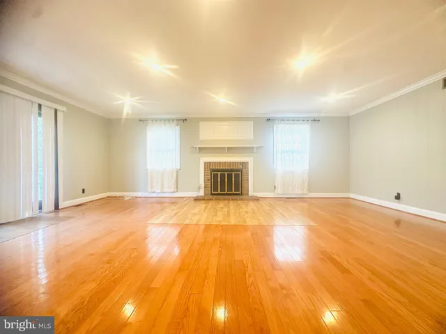 an empty room with a fireplace and wooden floor