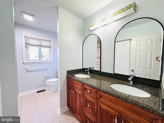 a bathroom with a granite countertop double vanity sink and mirror