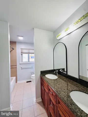 a bathroom with a granite countertop double vanity sink and a mirror