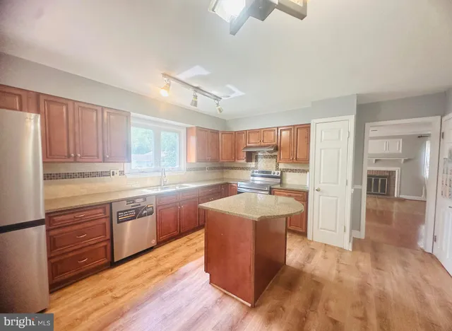 a large kitchen with cabinets wooden floor and stainless steel appliances