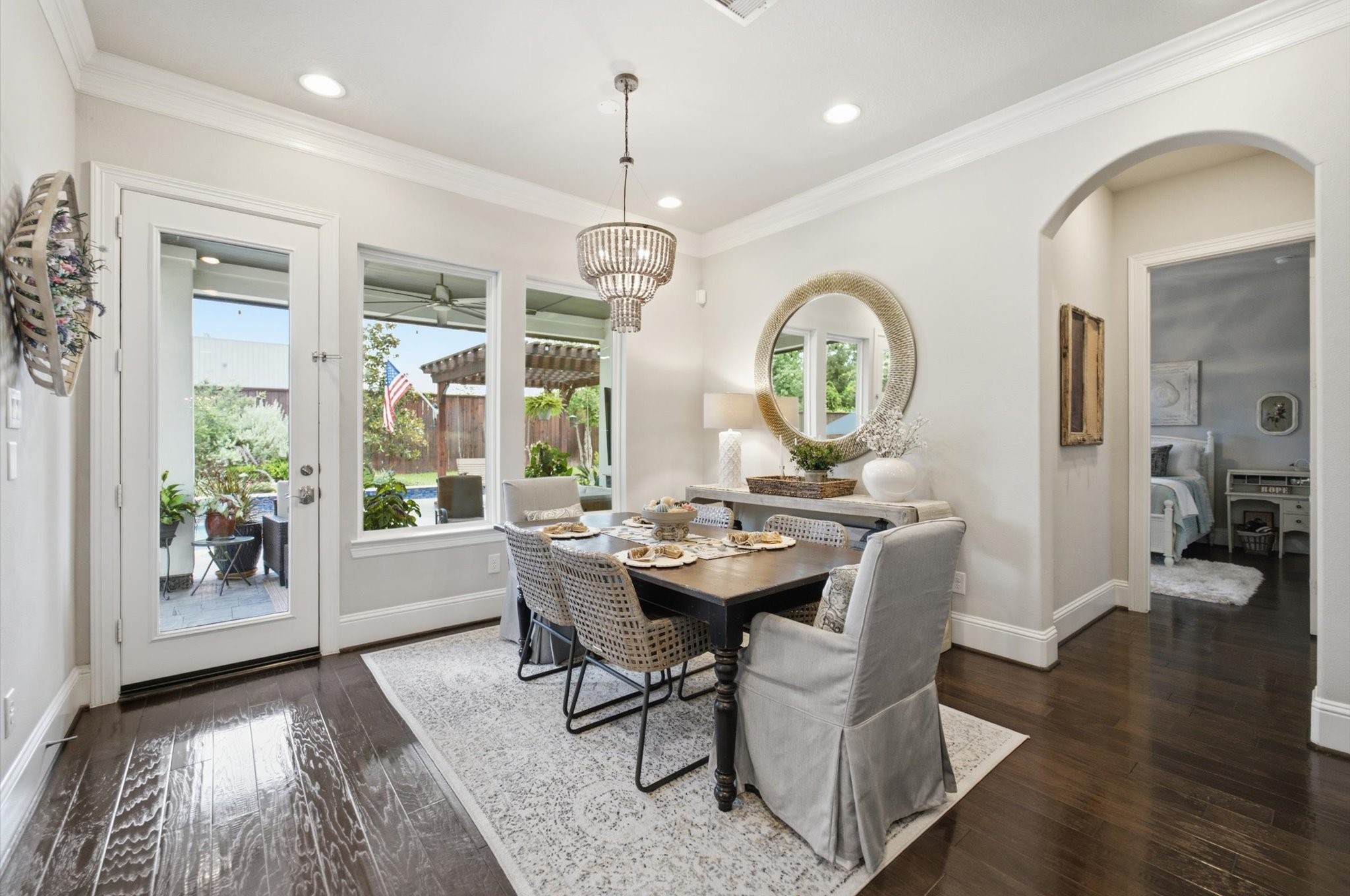 23722 Thortons Park Lane Spring, TX 77389 - Photo 24 of 48 Bright dining area with elegant hardwood floors, modern chandelier, and stylish decor. Large windows and glass door open to a lush outdoor patio, enhancing natural light and offering a seamless indoor-outdoor flow.