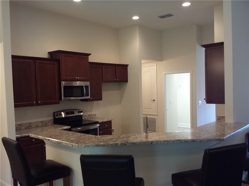 88397 Maybourne Road Yulee, FL 32097 - Photo 21 of 35 a kitchen with stainless steel appliances granite countertop a sink a stove a microwave a refrigerator and cabinets