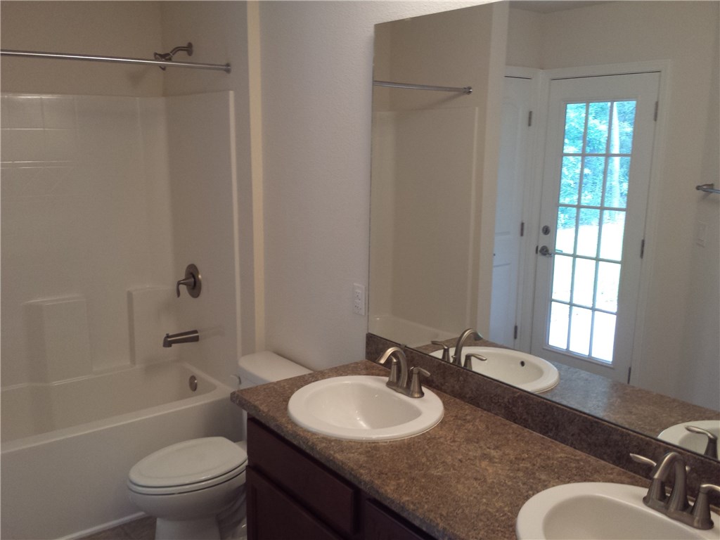 88397 Maybourne Road Yulee, FL 32097 - Photo 23 of 35 a bathroom with a granite countertop sink toilet a shower and a mirror