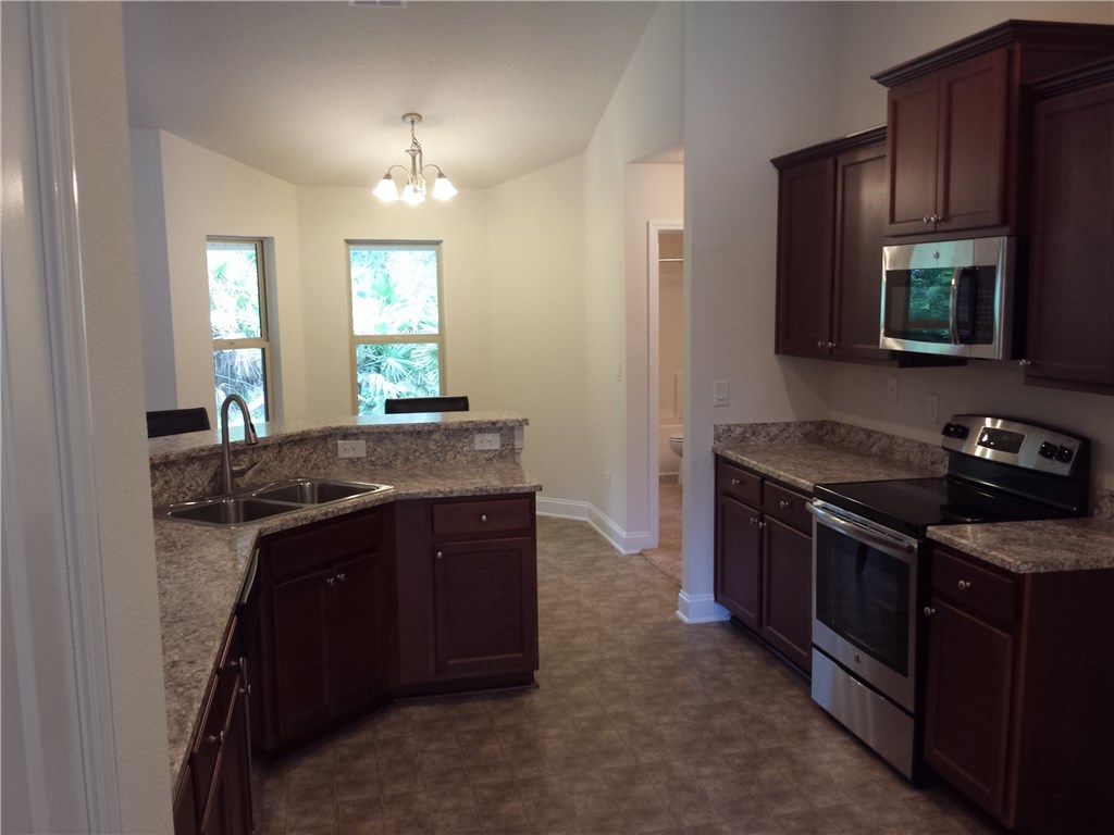 88397 Maybourne Road Yulee, FL 32097 - Photo 30 of 35 a kitchen with stainless steel appliances granite countertop a stove a sink and a microwave