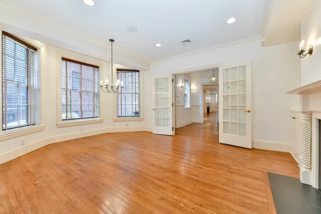a view of an empty room with window and wooden floor