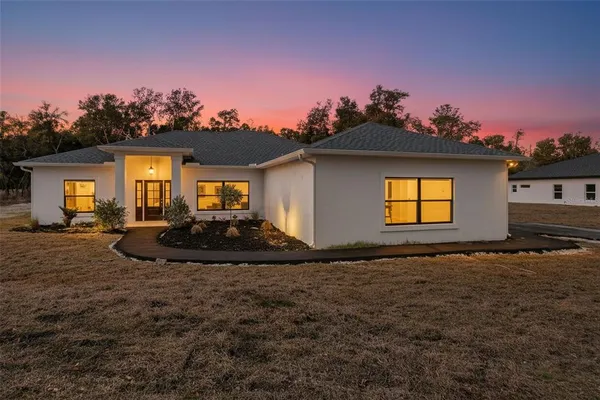 a view of a white house next to a yard with a potted plants