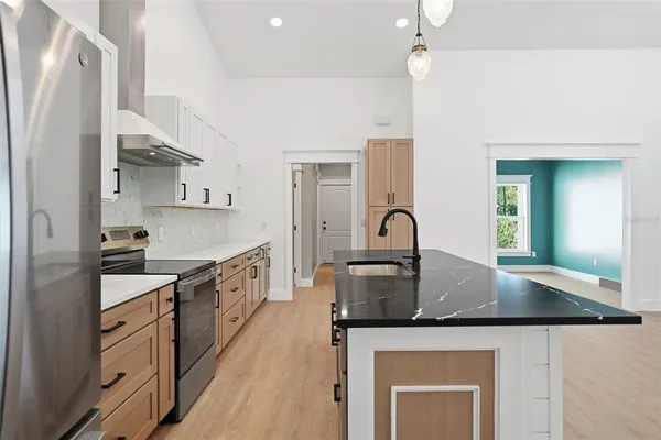 an empty room with wooden floor chandelier fan and windows