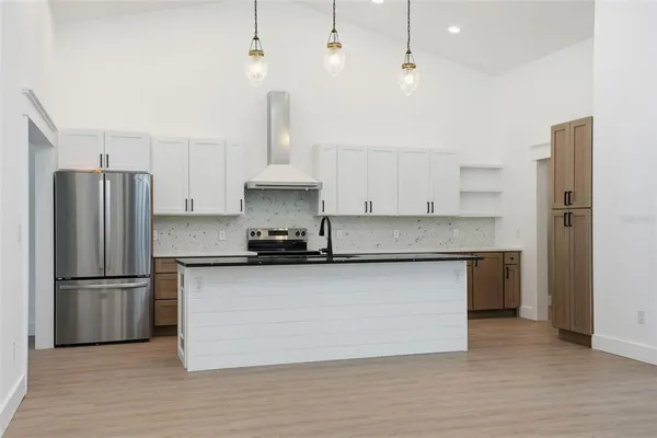 an empty room with wooden floor chandelier fan and windows