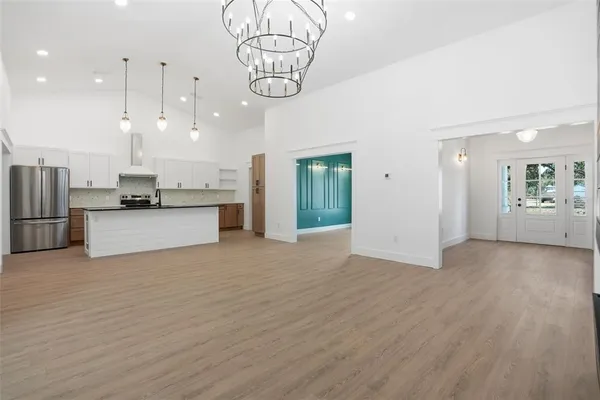 an empty room with wooden floor cabinet and windows