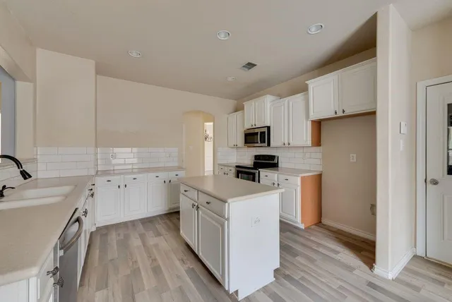 a kitchen with white cabinets sink and refrigerator