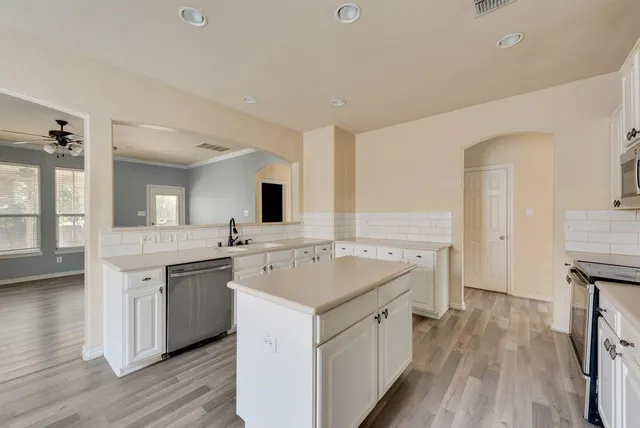 a kitchen with a sink and stove with wooden floor
