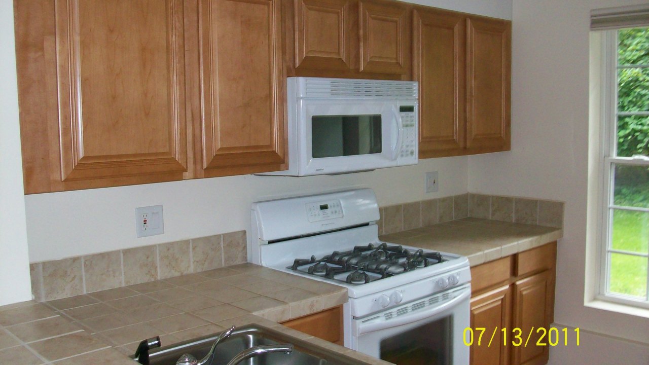 72 Interlaken Road, Unit 3 West Stockbridge, MA 01266 - Photo 1 of 10 a kitchen with granite countertop a stove top oven cabinetry a chimney and a window