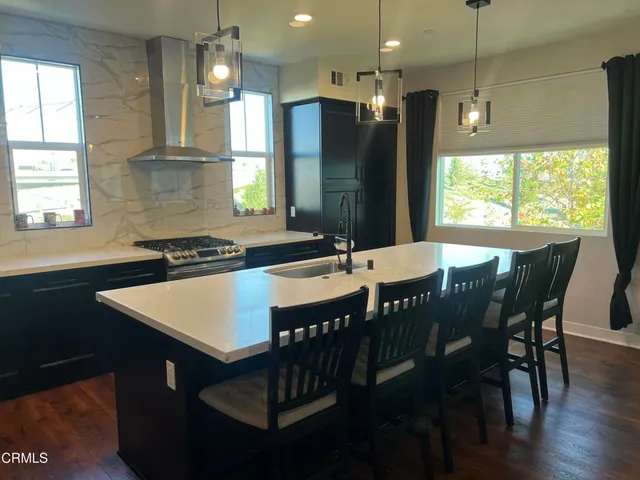 a kitchen with stainless steel appliances granite countertop a dining table chairs and a refrigerator