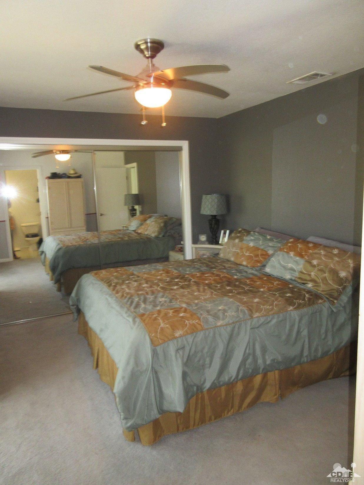 36915 Palmdale Road Rancho Mirage, CA 92270 - Photo 16 of 23 a bedroom with a bed and a chandelier