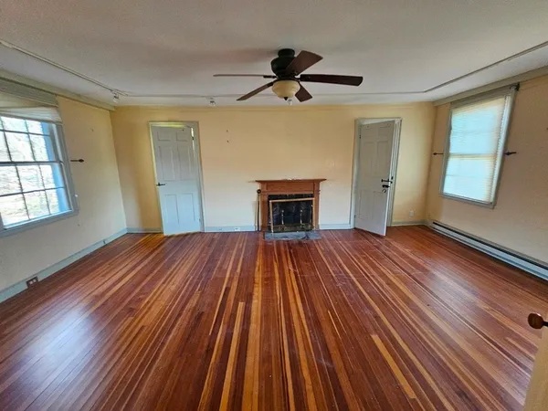a view of an empty room with wooden floor and a window