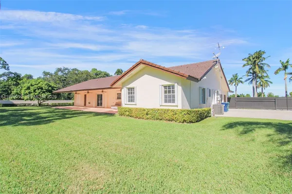 a view of a yard in front of a house with a large tree