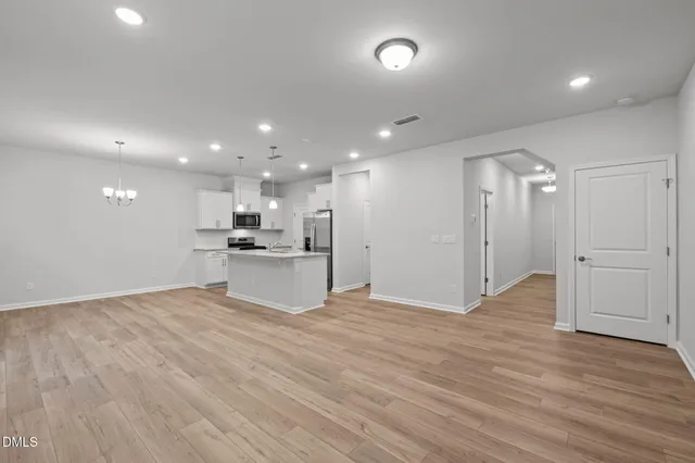 a view of kitchen with kitchen island a sink wooden floor and stainless steel appliances